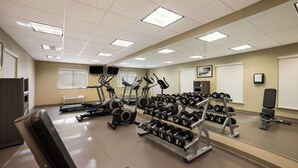 A gym with treadmills, elliptical machines, and a rack of dumbbells.