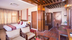 A hotel room with a bed, a sofa, a dining table, and a kitchen area. - Hotel Marshyangdi (Kathmandu)