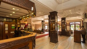 A lobby with a reception desk, wooden decor, and a marble floor. - Hotel Marshyangdi (Kathmandu)