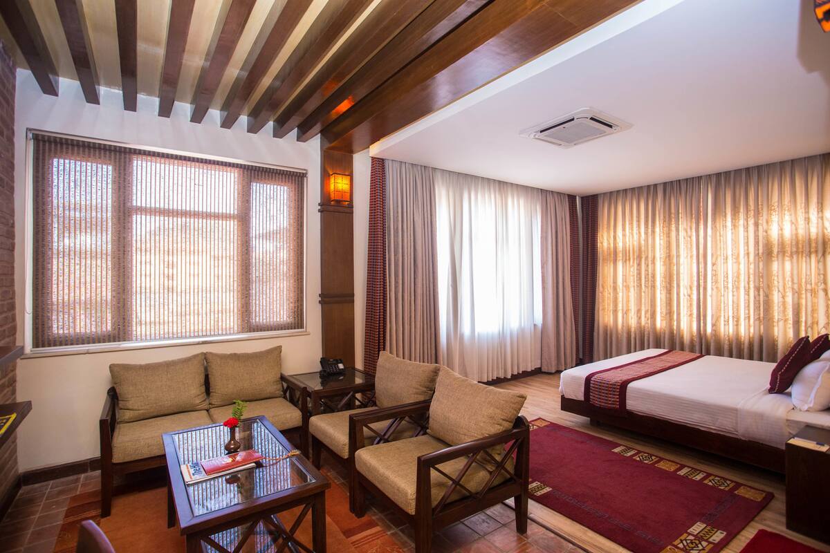 A hotel room with a bed, sofa, and a small table with a vase and book.