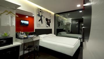 A modern hotel room with a bed, desk, and TV.
