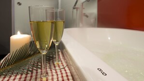 Two glasses of champagne on a checkered tablecloth beside a bathtub with the brand name "Oxo". - Venue Hotel (Singapore)