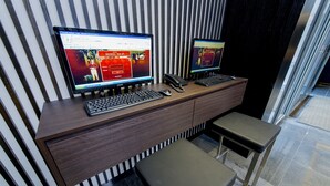 A modern desk with two monitors, a keyboard, a phone, and a small stool. - Hotel 81 Premier Star (Singapore)