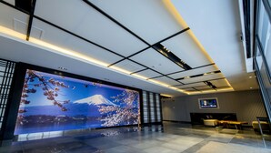 A modern lobby with a large digital display of Mount Fuji and cherry blossoms, a seating area, and a television screen. - Hotel 81 Premier Star (Singapore)