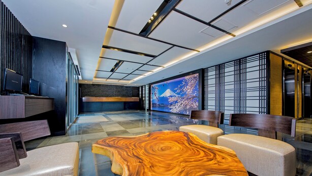 A modern lobby with a large wooden coffee table, seating area, and a large screen displaying a scenic image. - Hotel 81 Premier Star (Singapore)