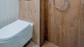 A modern bathroom with a wooden wall, a shower, a toilet, and a towel rack.