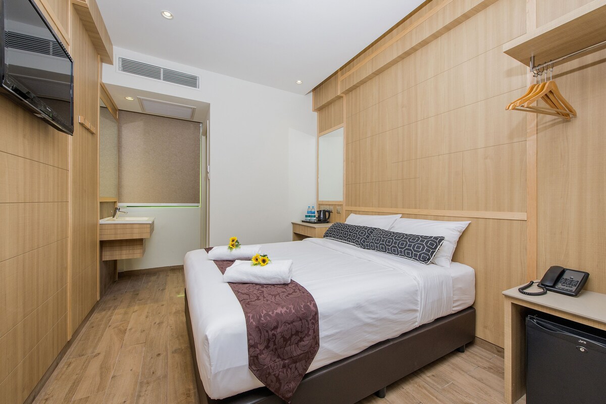 Una habitación de hotel con cama, mesita de noche y espejo.