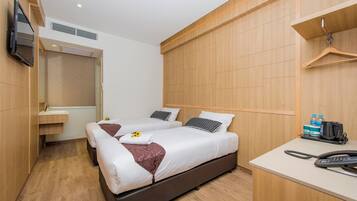 A hotel room with two beds, a desk with a telephone, and a television mounted on the wall.
