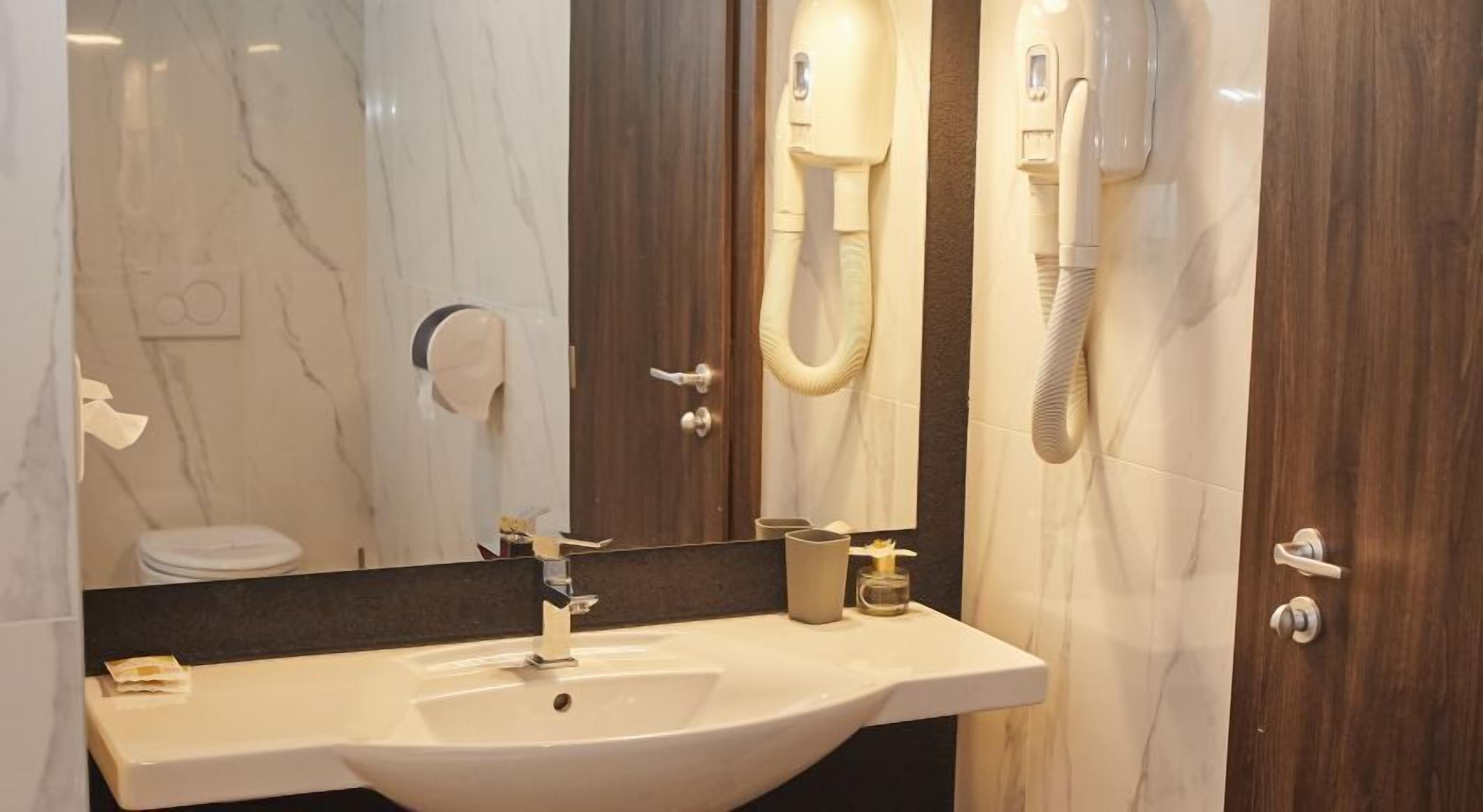 Un baño con tocador de mármol, un lavabo, un espejo, un dispensador de toallas y un secador de pelo.