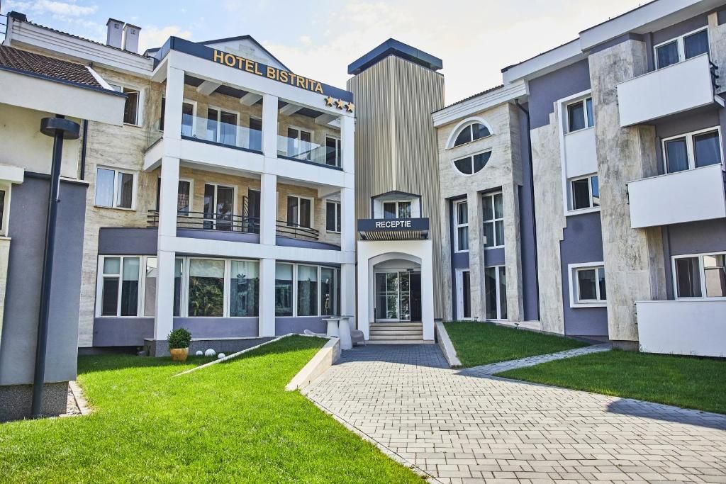 A hotel with a reception area, multiple floors, and a well-maintained lawn.