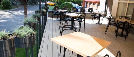 An outdoor patio with wooden flooring, metal chairs, and tables.