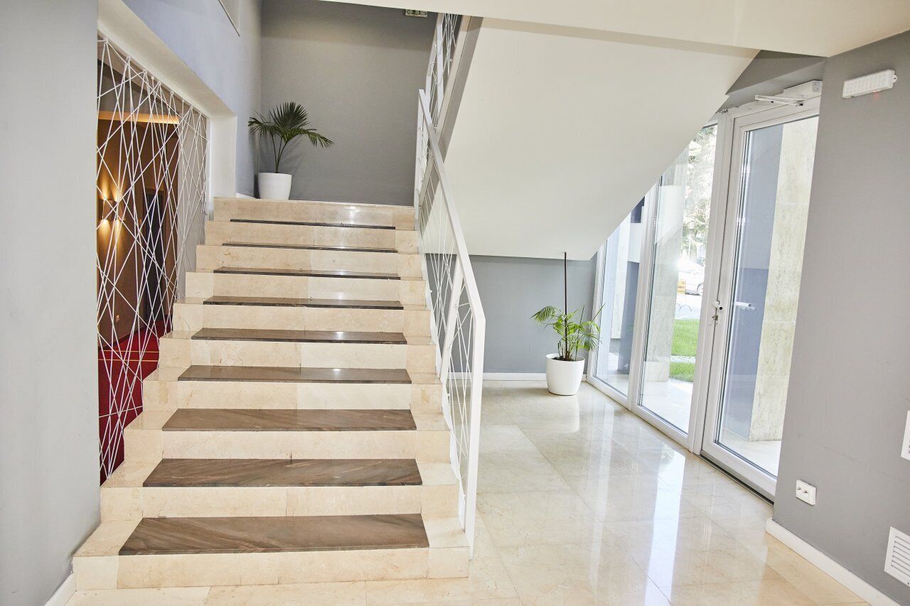 Ein modernes Interieur mit einer Marmortreppe, einem geometrischen Wanddesign und einer Topfpflanze.