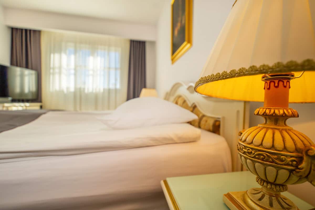 A hotel room with a bed, a lamp, and a television.