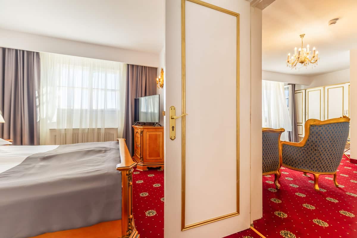 A hotel room with a large bed, a desk with a computer, a chair, and a wardrobe.