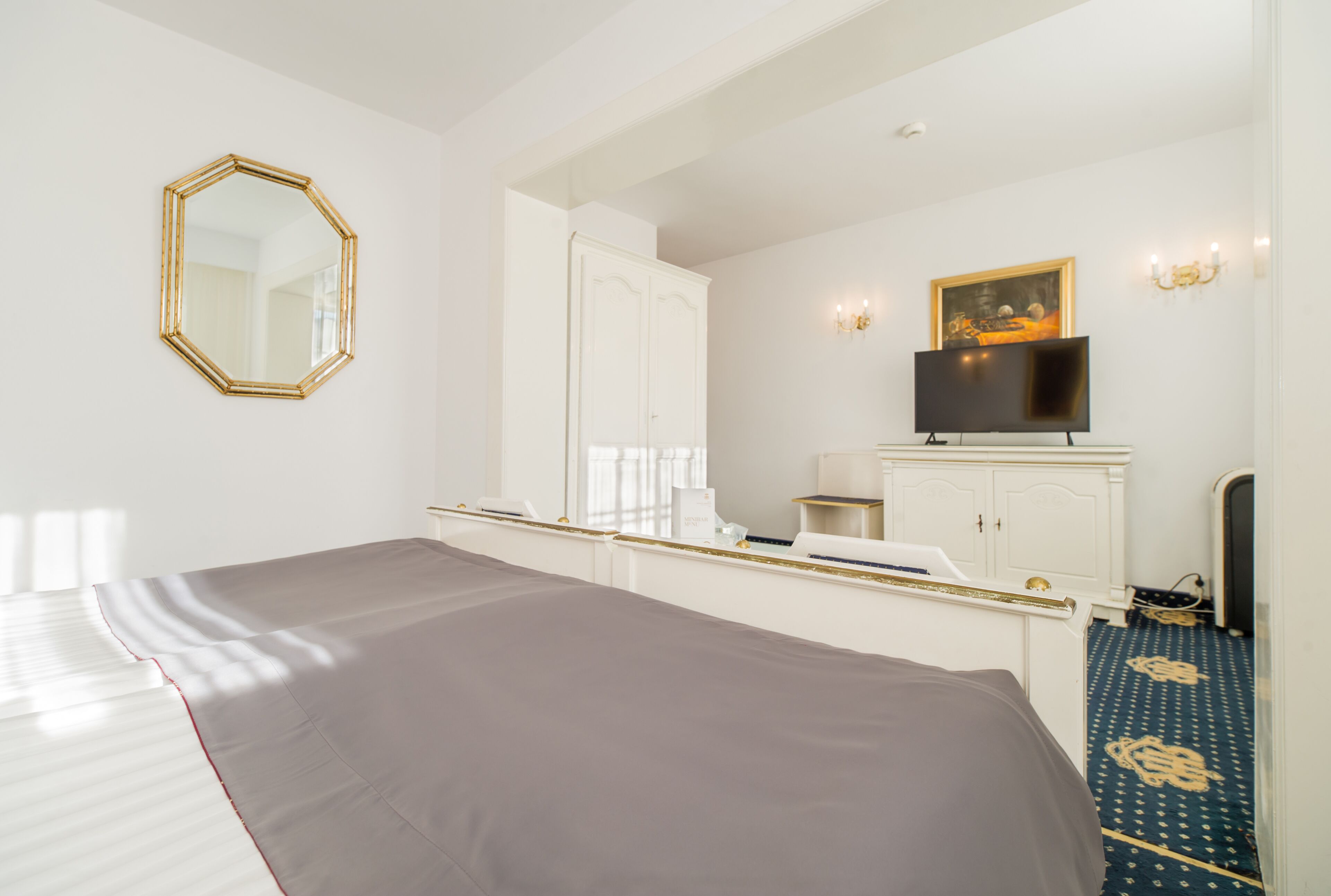 Una habitación de hotel con una cama grande, un armario, un televisor y un espejo.