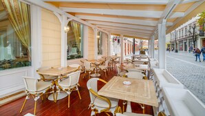An indoor cafe with white wicker furniture and large windows. - Hotel Imparatul Romanilor (Sibiu)
