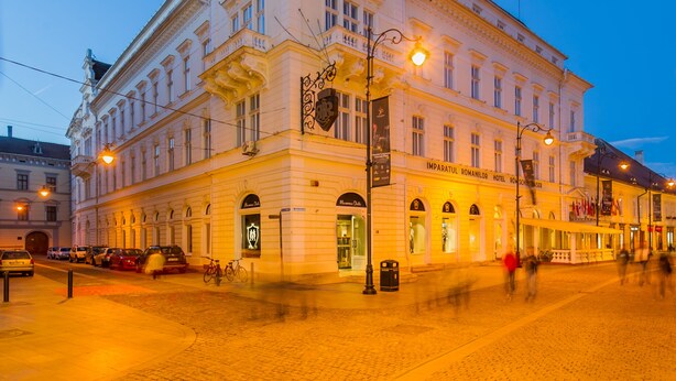 A historic building with classical architecture, a prominent entrance, and a sign indicating it is a hotel. - Hotel Imparatul Romanilor (Sibiu)
