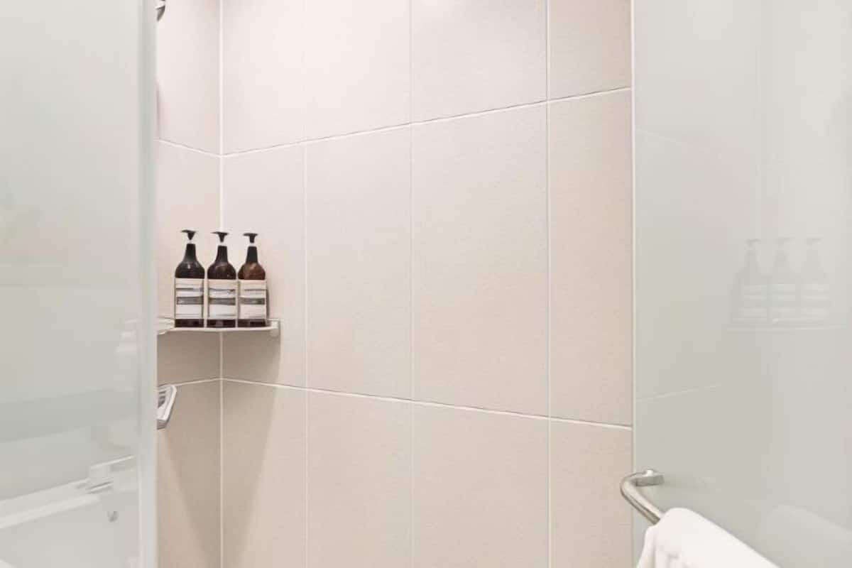Badkamer | Een aparte badkuip en douche, een haardroger, pantoffels