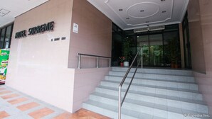 Ein Hotel Eingang mit Namensschild, einer Treppe und Blumentöpfen.