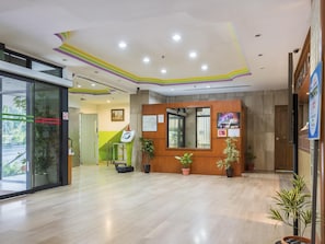 A reception area with a wooden reception desk, a large mirror, potted plants, and a wheelchair-accessible ramp.