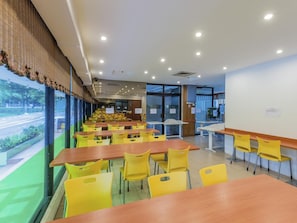 A dining area with tables and chairs, a view of the street, and a large window with a view. - Hotel Supreme (Singapore)