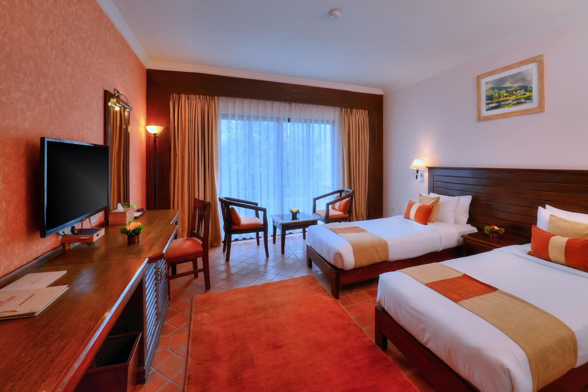 A hotel room with two beds, a TV, a desk, and a chair.