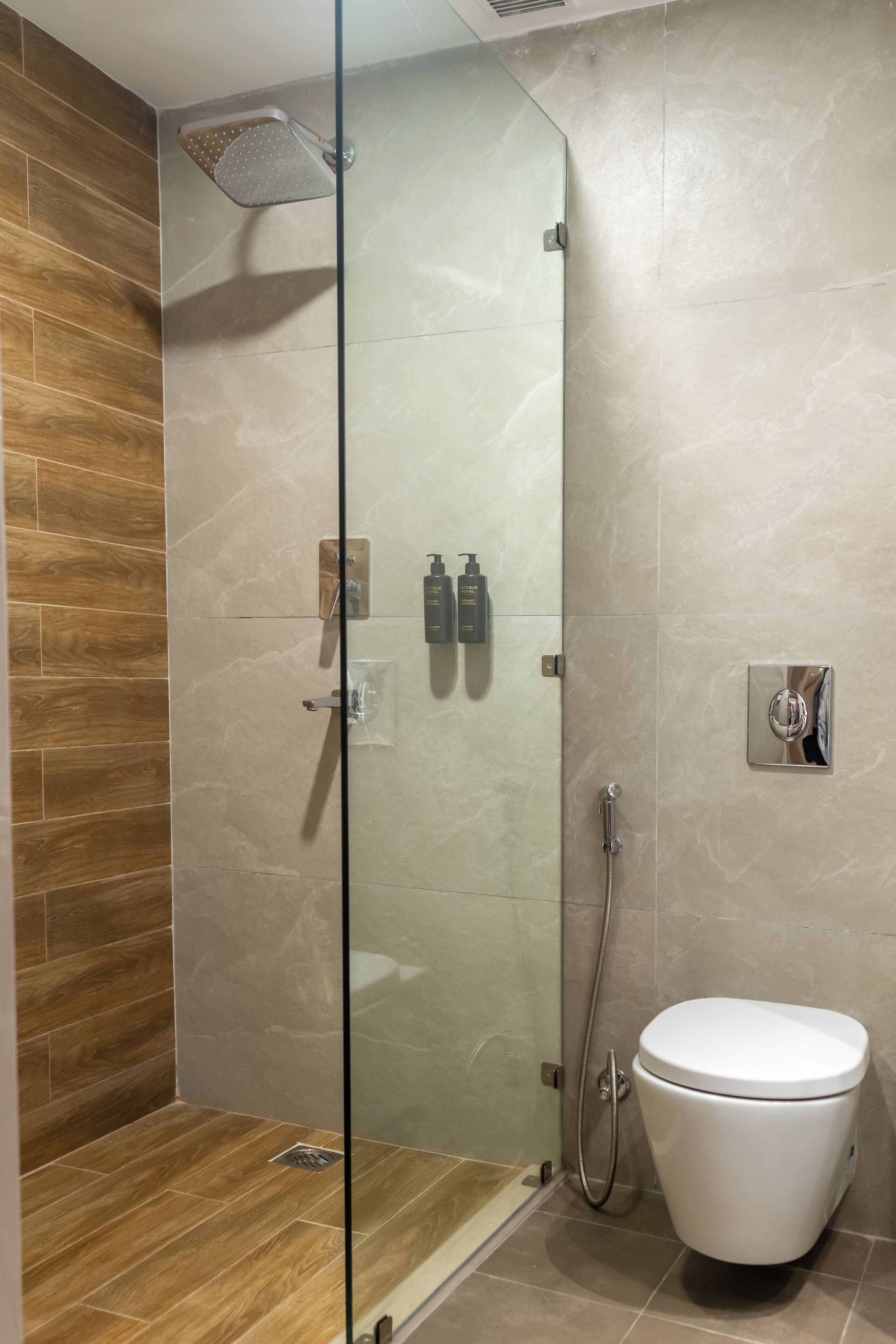 A modern bathroom with a glass-enclosed shower, a toilet, and a wooden floor.