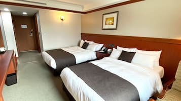 A hotel room with two beds, a desk, a phone, and a framed picture on the wall.