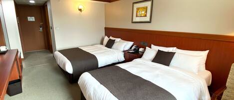 A hotel room with two beds, a desk, a phone, and a framed picture on the wall.