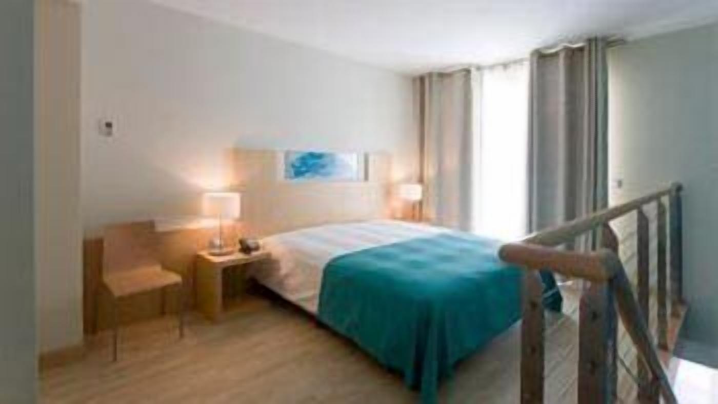 Una habitación de hotel con cama, mesitas de noche, una silla y vistas al exterior.