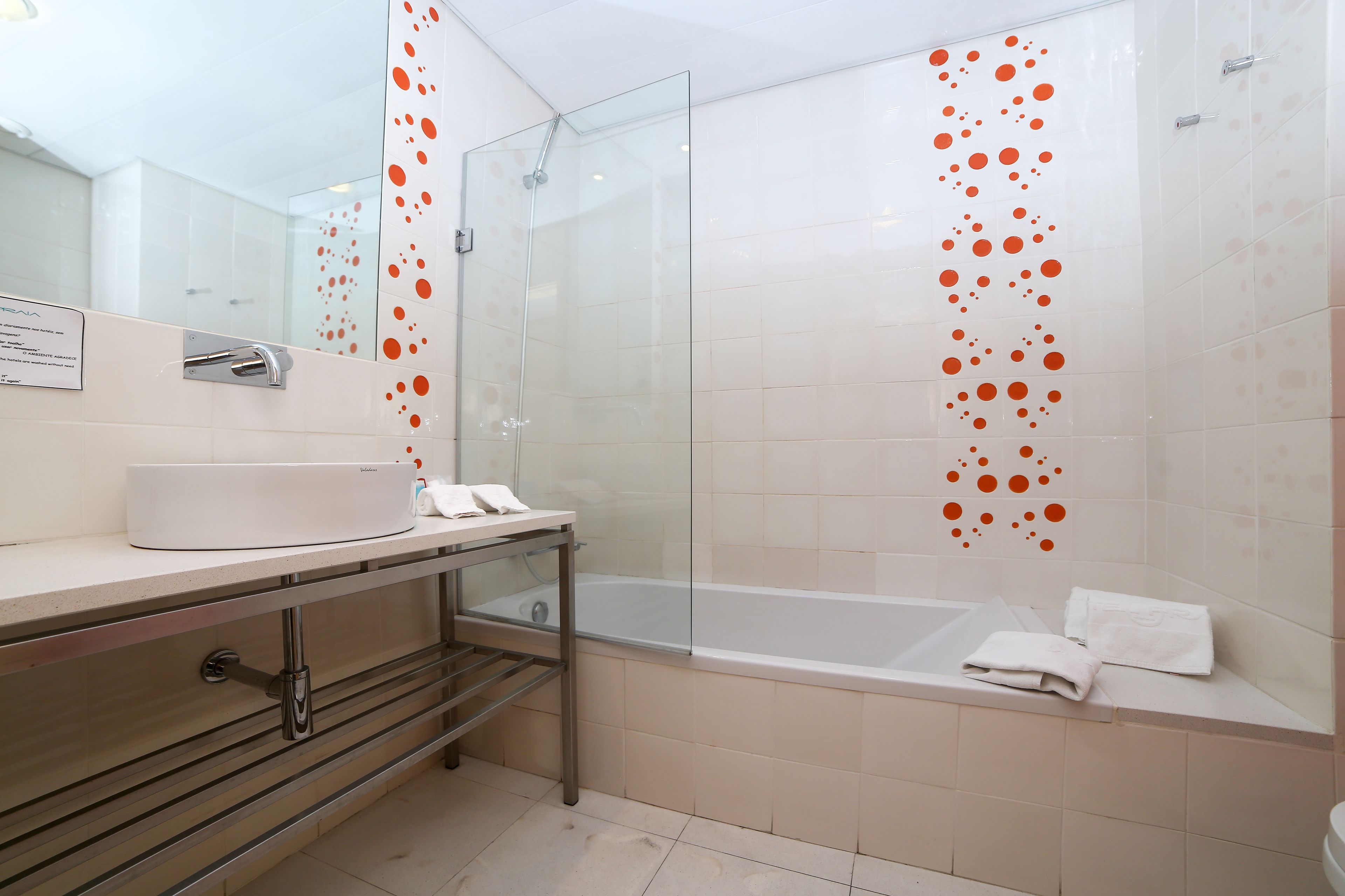 A modern bathroom with a glass shower enclosure, a bathtub, and a vanity with a sink and towel rack.