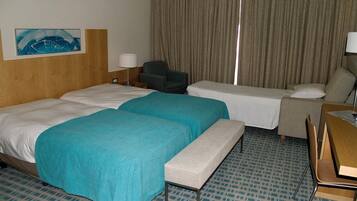 A hotel room with two beds, a desk, a chair, and a large window with curtains.