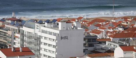 A coastal hotel with red-tiled roofs, a prominent 'HOTEL' sign, and a view of the ocean.