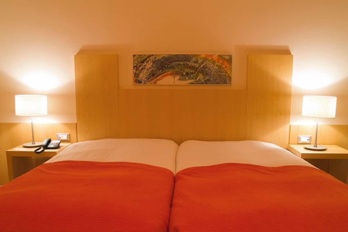 Ein Doppelbett mit Holzvorhang, zwei Nachttische mit Lampen und ein Gemälde über dem Vorhang.