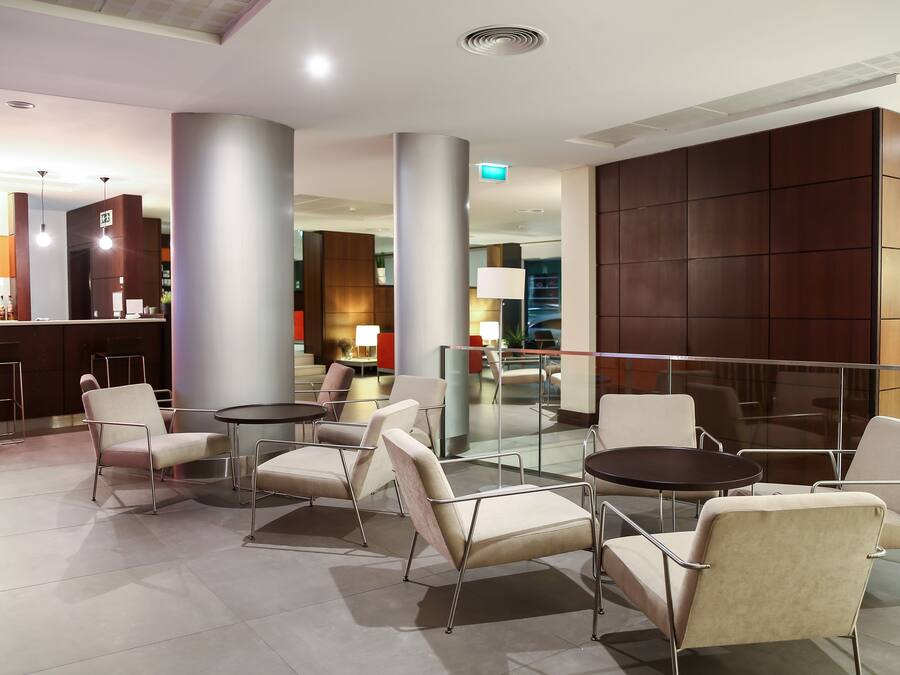 A modern lobby with seating areas, a bar, and a staircase.