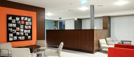 A modern waiting area with a reception desk, seating, and a large abstract artwork on the wall.