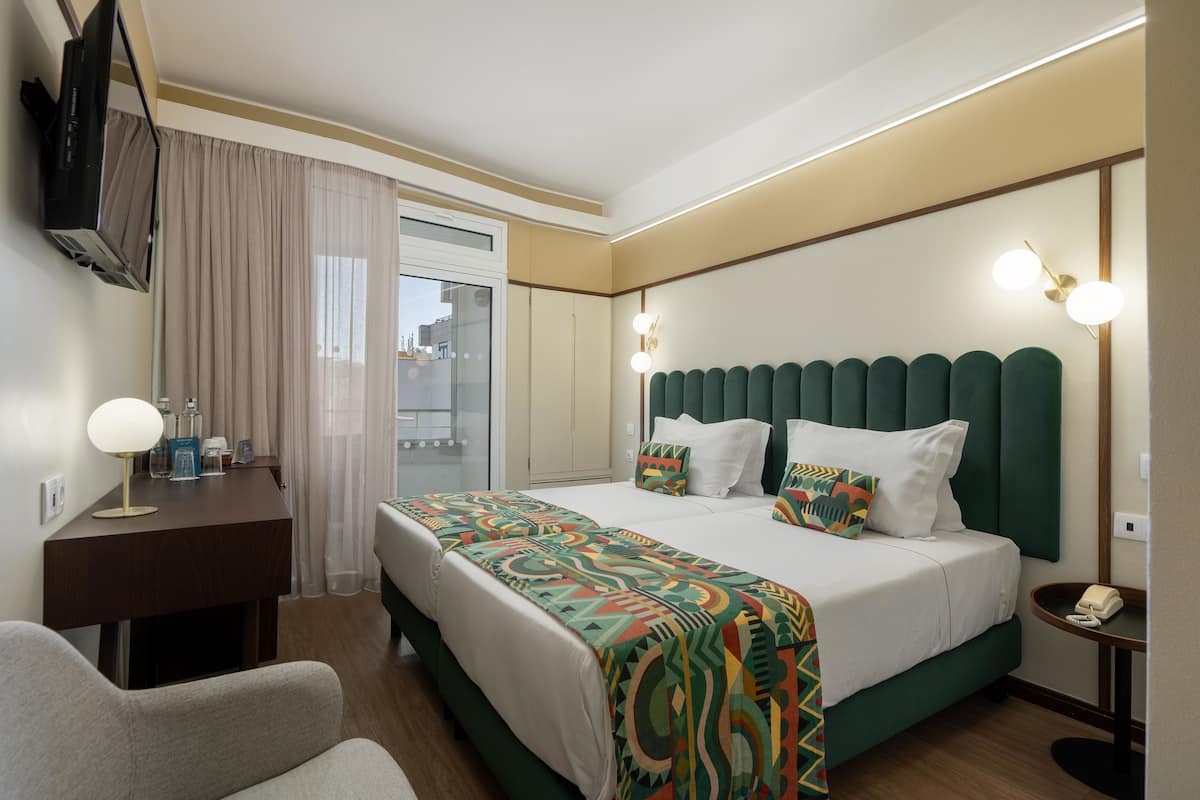 Ein Hotelzimmer mit Bett, Schreibtisch, Stuhl, Fernseher und Telefon.