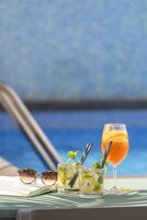 Ein Poolbereich mit Getränkekarte, Sonnenbrille und einem Glas Orangecocktail.