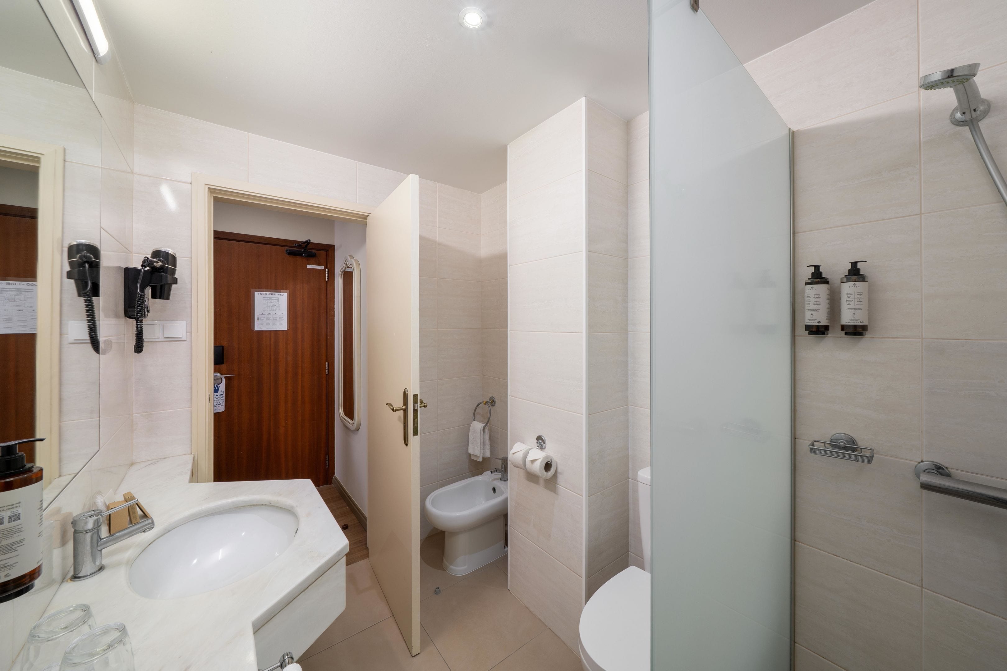 A modern bathroom with a sink, toilet, bidet, and shower.