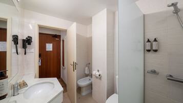 A modern bathroom with a sink, toilet, bidet, and shower.