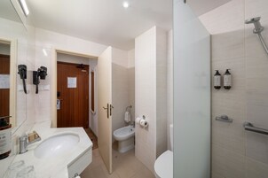 A modern bathroom with a sink, toilet, bidet, and shower.