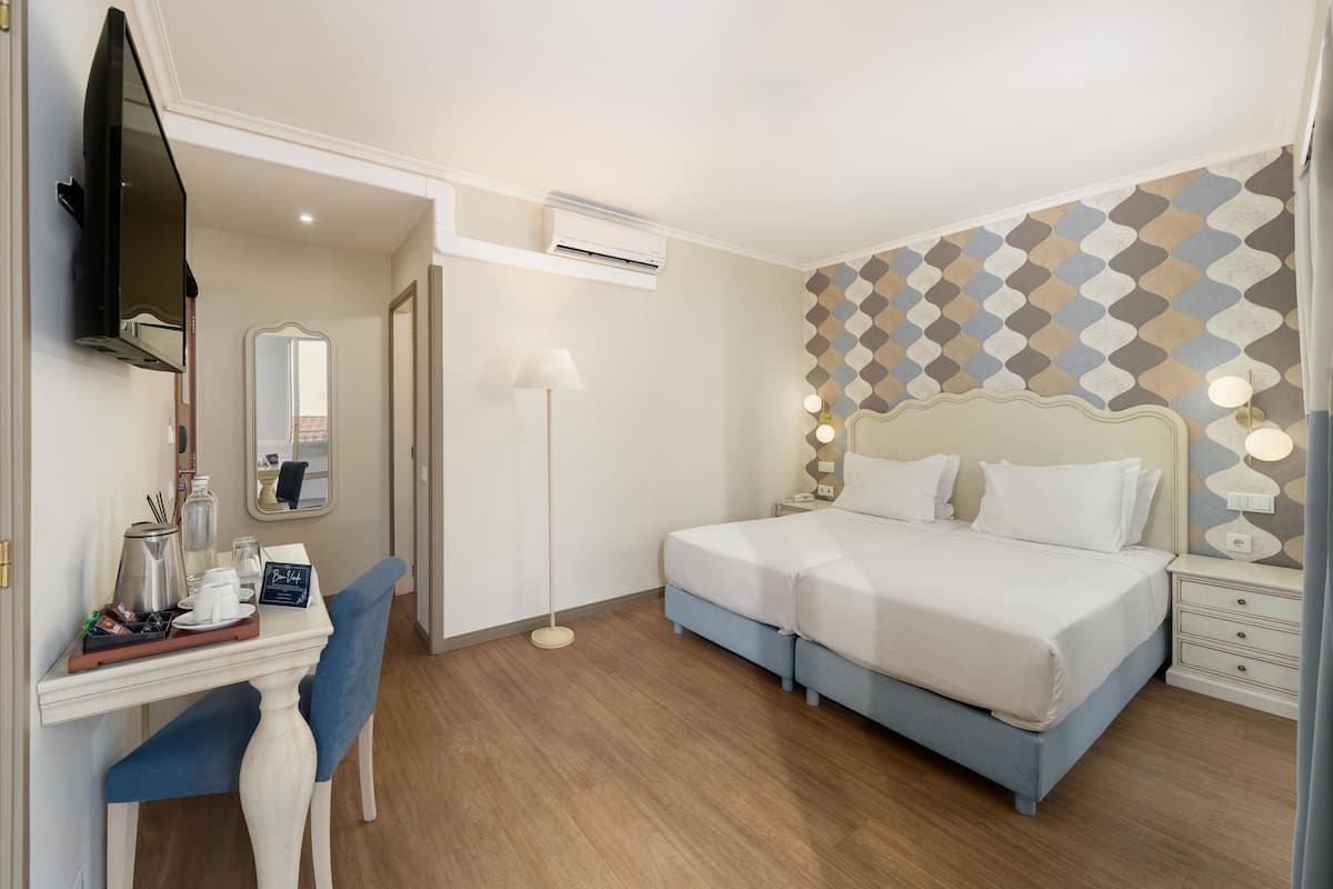 Ein Hotelzimmer mit Bett, Nachttisch, Lampe und Schreibtisch mit Stuhl.