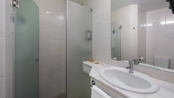 Een moderne badkamer met een douchecabine van glas, een wit wastafelmeubel en een grote spiegel.