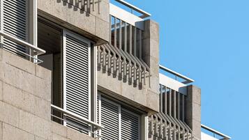 A modern building with multiple balconies, large windows, and a clear blue sky.