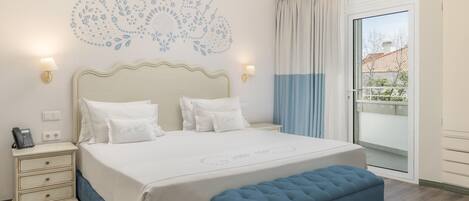 A neatly arranged bedroom with a large bed, bedside lamps, a bedside phone, and a window with curtains.