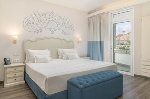 A neatly arranged bedroom with a large bed, bedside lamps, a bedside phone, and a window with curtains.