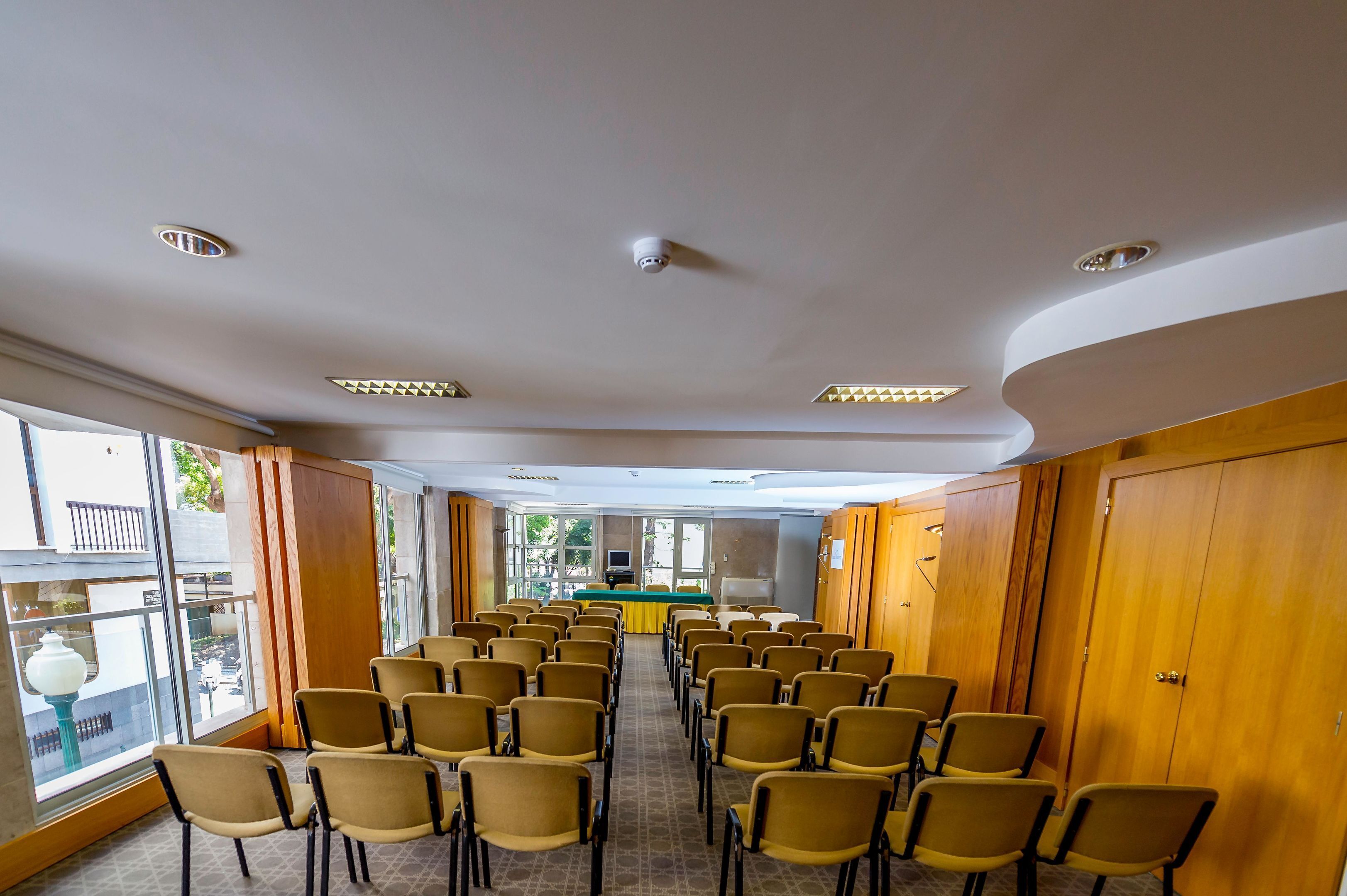 A conference room with rows of chairs facing a table with a speaker's podium.