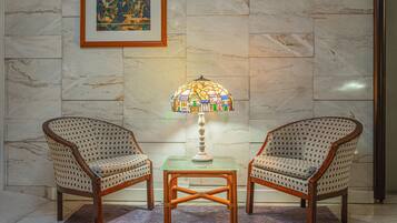 Deux fauteuils en osier, une table en verre et une lampe à motifs de mosaïque placés entre eux.