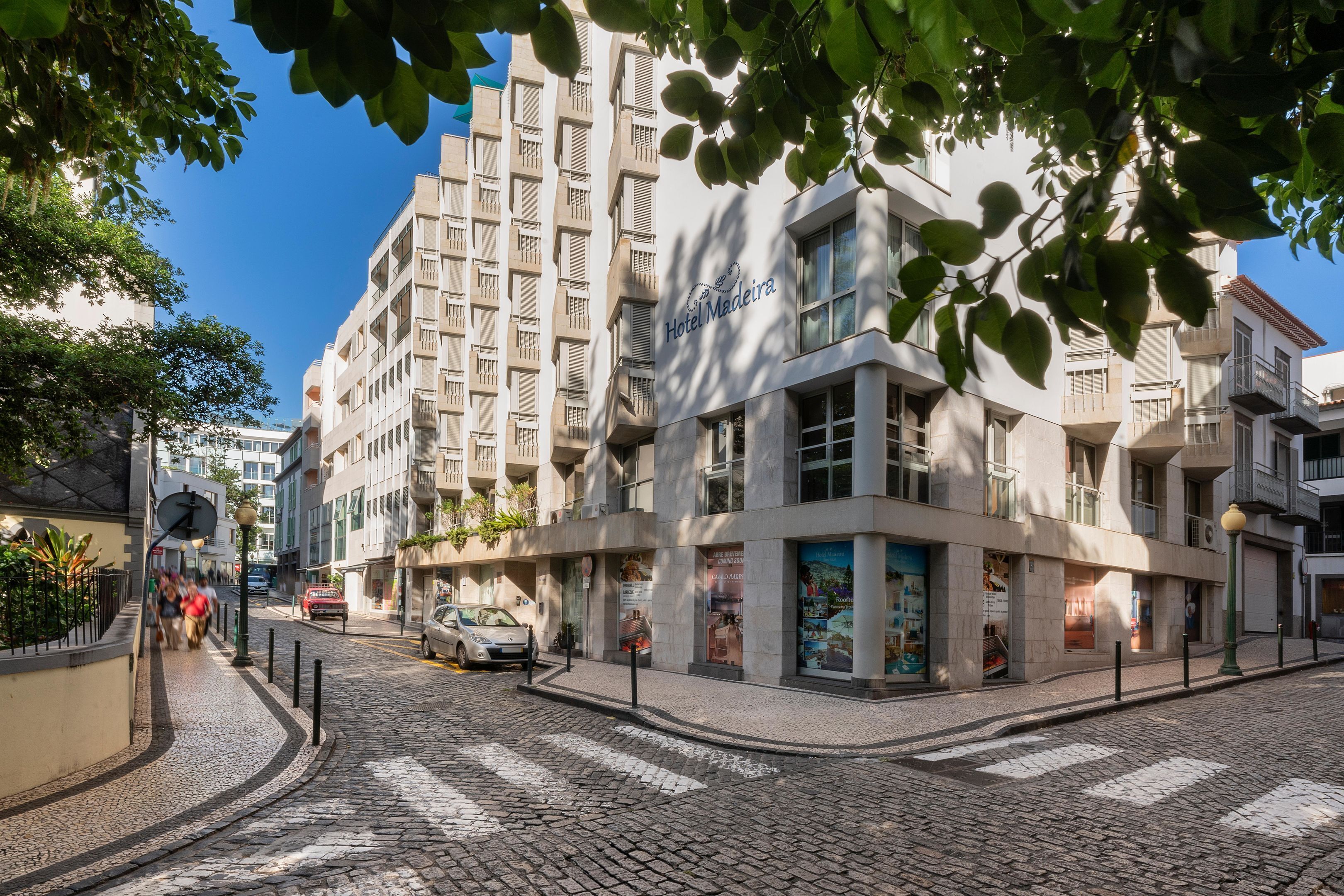 A hotel with a modern facade, a cobblestone street, and a pedestrian crossing.