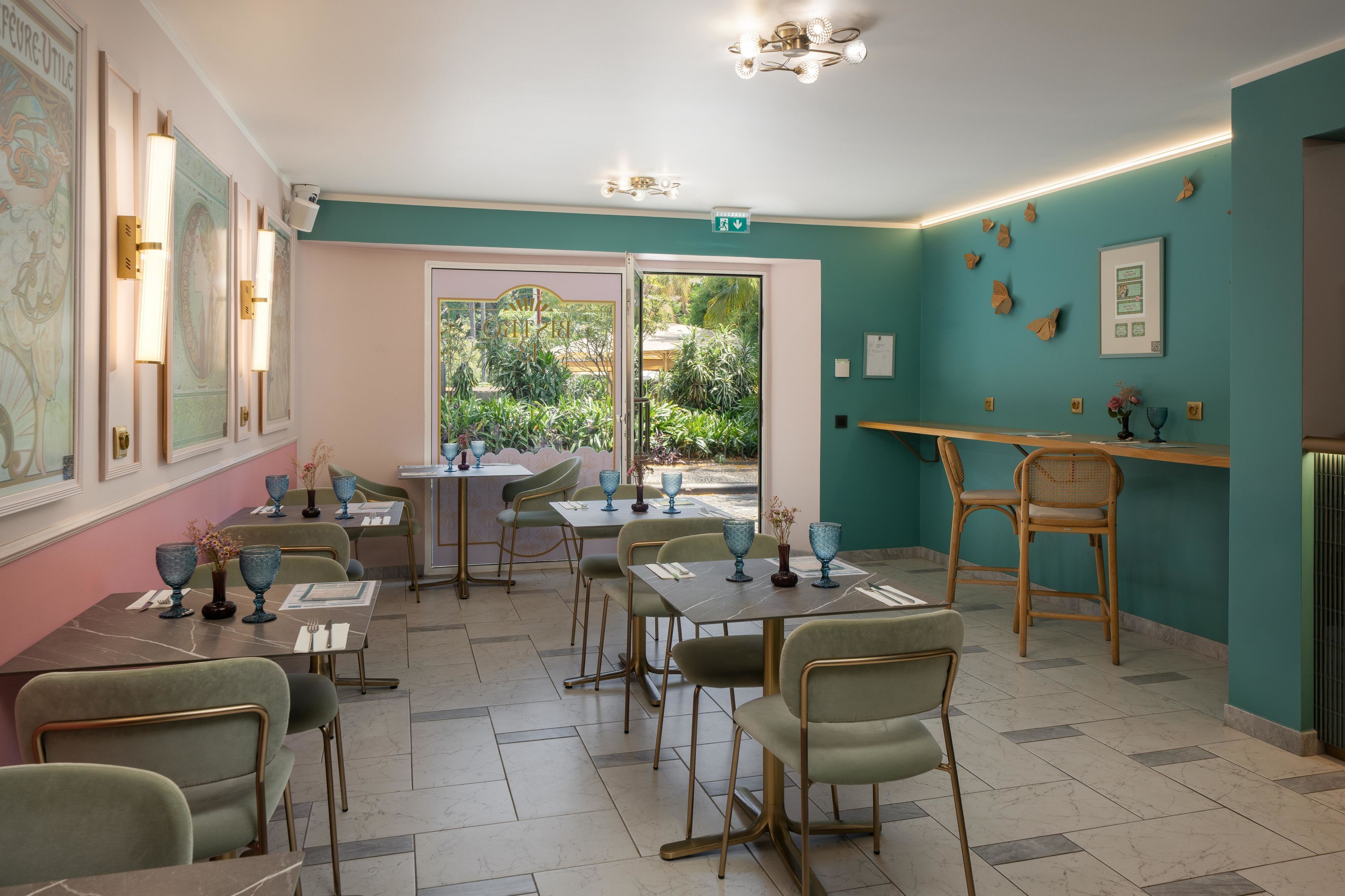 A restaurant with tables and chairs, a counter, and a view of greenery outside.